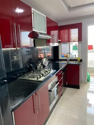 a kitchen with red cabinets and a stove top oven at Magnifique F3 rénové Fibre, Parking & excellente desserte in Casablanca