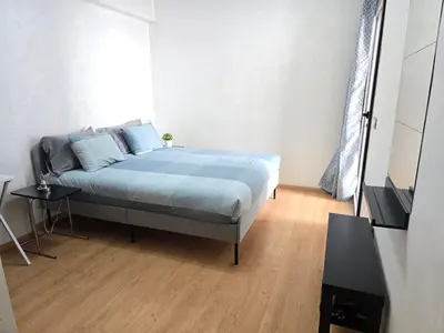 a bedroom with a bed with blue sheets and a wooden floor at Joli appartement Mohammédia in Mohammedia