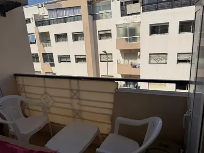 a balcony with two chairs and a window with a building at Résidence jnane California in Casablanca