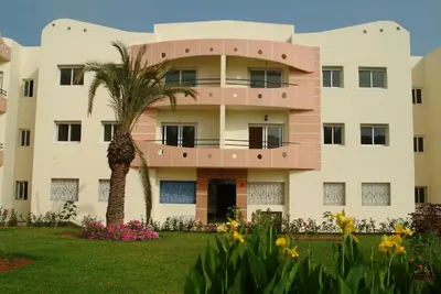 a building with a palm tree in front of it at Appartement Mimousa in Mohammedia