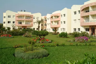 an apartment building with a garden in front of it at Appartement Mimousa in Mohammedia