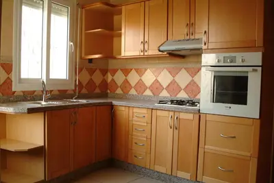 a kitchen with wooden cabinets and a sink and a microwave at Appartement Mimousa in Mohammedia
