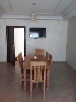 a wooden table and chairs in a living room at Appartement 2 chambres Bouznika in Bouznika