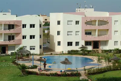 a resort with a large pool in front of a building at Les vacances verdoyantes MOHAMMEDIA in Mohammedia