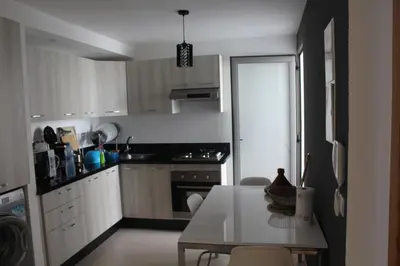 a kitchen with white cabinets and a table with chairs at Paradise BEACH in Mohammedia