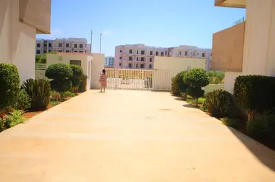 a child walking down a walkway between buildings at MOHAMMEDIA L Oasis maritime in Mohammedia