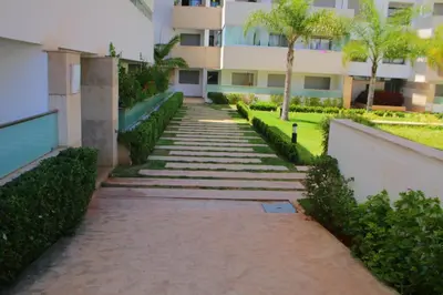a walkway in front of a building with trees at MOHAMMEDIA L Oasis maritime in Mohammedia