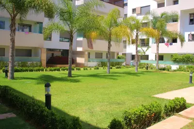 a park in front of a building with palm trees at MOHAMMEDIA L Oasis maritime in Mohammedia