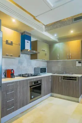 a kitchen with wooden cabinets and a stove top oven at Massira Diamond Maarif- Parking-wifi-self check in in Casablanca