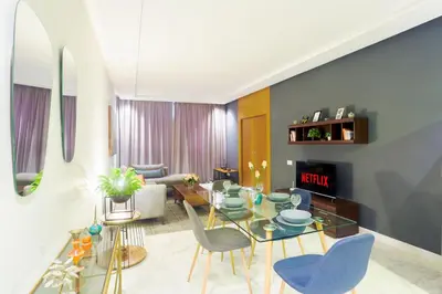 a living room with a glass table and blue chairs at Lavish Flat in new city #fastwifi#Parking in Casablanca