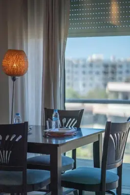a dining room table and chairs with a lamp and a window at Racine bd anfa Appart style tokyo near twin center in Casablanca
