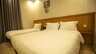 two beds in a hotel room with white sheets at Hotel de paris in Casablanca