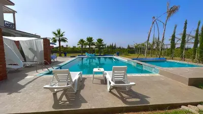 a swimming pool with four chairs and a table and a tablektop at Dar Ghita en campagne in O Ben Slimane