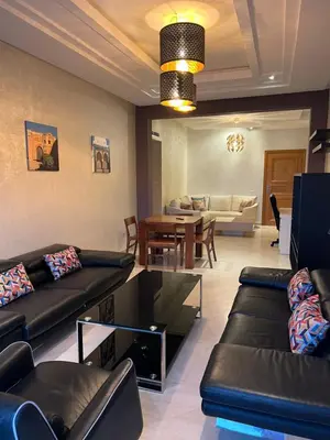 a living room with black leather couches and a dining room at PERLA NOUACEUR AéROPORT MOHAMMED V in Nouaceur