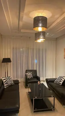 a living room with black furniture and a chandelier at PERLA NOUACEUR AéROPORT MOHAMMED V in Nouaceur