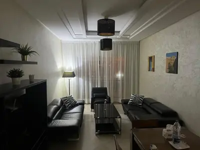 a living room with black leather couches and a table at PERLA NOUACEUR AéROPORT MOHAMMED V in Nouaceur