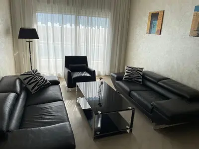 a living room with a black leather couch and a chair at PERLA NOUACEUR AéROPORT MOHAMMED V in Nouaceur