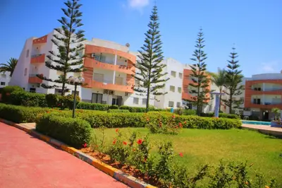 a park in front of a building with trees and flowers at MOHAMMEDIA 304 in Mohammedia