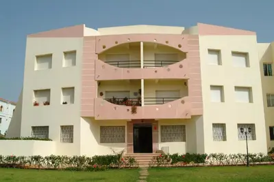 a pink building with a round window at Appartement sable et soleil in Mohammedia