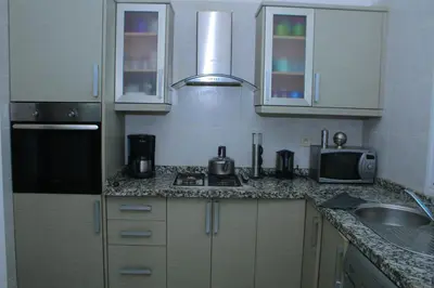 a kitchen with white cabinets and a sink and a microwave at MOHAMMEDIA Residence KAWTAR in Mohammedia
