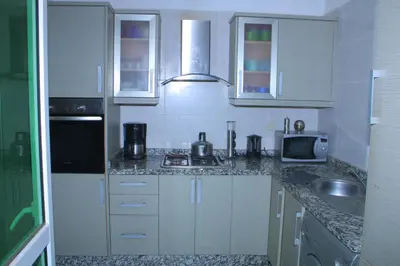 a kitchen with white cabinets and a sink and a microwave at MOHAMMEDIA Residence KAWTAR in Mohammedia