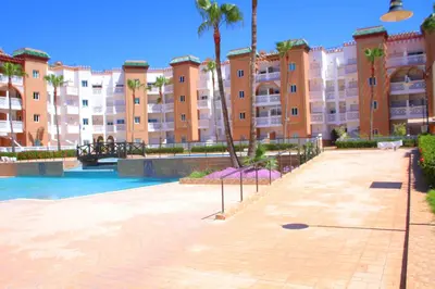 a large apartment building with a swimming pool and palm trees at MOHAMMEDIA Residence KAWTAR in Mohammedia