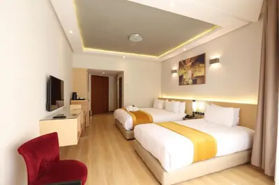 a hotel room with two beds and a chair at Silver Suites Hotel & Spa Casablanca in Casablanca