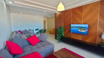 a living room with a couch and a tv on a wall at bouzkina Costa beach golf in Bouznika