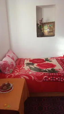 a bed with a red comforter and a table at Khaima in Souk Jemaa des Oulad Abbou