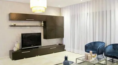 a living room with two blue chairs and a television at #10 Racine triangle d or near aindiab in Casablanca