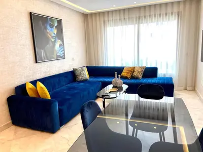 a living room with a blue couch and a glass table at Anfa Living 11 - Classy & Élégant near the Sea in Casablanca