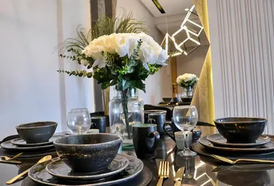 a table with plates and a vase with white flowers at ANFA LIVING - Front Sea VIEW 180 -2 or 3 bedrooms- LES TERRASSES D'ANFA by ShortStayMaroc in Casablanca