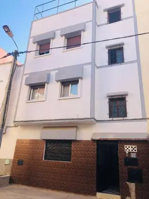 a tall white building with windows on a street at Les Appartements de Massira in Temara