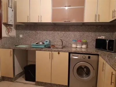a kitchen with a washing machine and a sink at Les Appartements de Massira in Temara