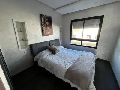 a bedroom with a bed and a window at Appartement front de mer avec piscine en face des plages privées in Dar Bouazza