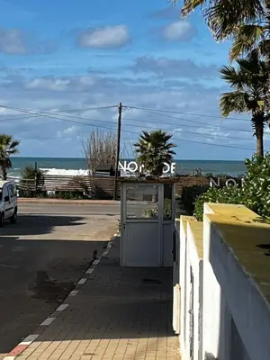 a bus stop with the beach in the background at Appartement front de mer avec piscine en face des plages privées in Dar Bouazza