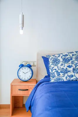 a blue alarm clock sitting on a table next to a bed at #13 Fresh Appart in new residence in Casablanca