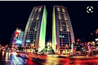 two tall buildings on a city street at night at Grand Appartement à 5 min de la mer et de la mosqué hassan II de Casablanca in Casablanca