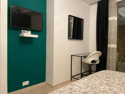 a bedroom with a green wall with a chair and a television at Appartement Anfa Park casa finance City CFC in Casablanca