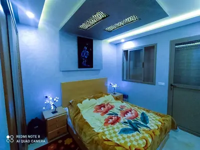 a bedroom with a bed with flowers on it at Appartement à Bouznika prêt du plage Dahomey, plage bouznika, Bahia beach in Bouznika