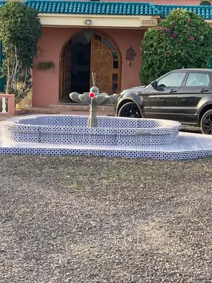 a fountain in front of a house with a car at Atlantic Vacation villa in Dar Oulad Hajj Kassem