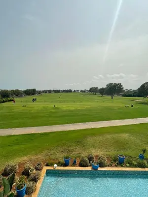 a pool with a view of a field and a rainbow at Havre de paix au BahiaGolf Beach, Résidence Front Mer in Bouznika