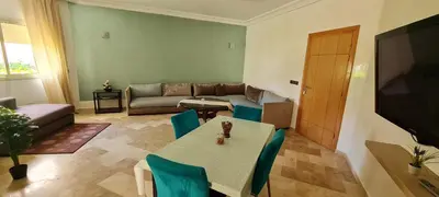 a living room with a table and a couch at Bel appartement Savannah Beach in Sidi Rahal