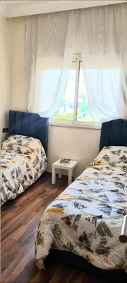 a bedroom with two beds and a window at Bel appartement Savannah Beach in Sidi Rahal