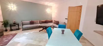 a living room with a table and a couch at Bel appartement Savannah Beach in Sidi Rahal