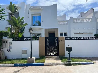 a white house with a gate and a street light at Villa avec piscine privée près de Casablanca Maroc in Dar Bouazza