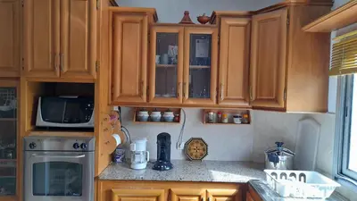 a kitchen with wooden cabinets and a microwave at Adarissa House in Rabat