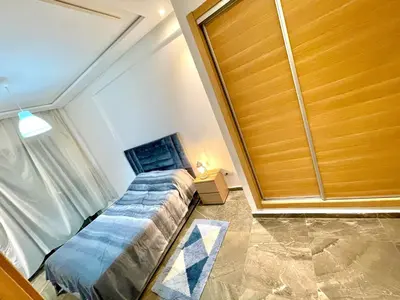 a bedroom with a bed and a wooden door at Bel Appartement à AMWAJ Sidi rahal in Casablanca