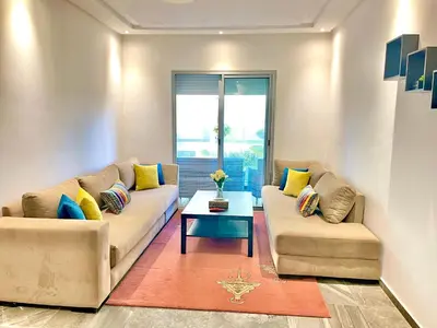 a living room with two couches and a table at Bel Appartement à AMWAJ Sidi rahal in Casablanca