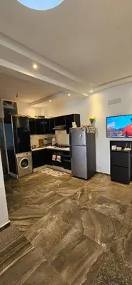 a room with a kitchen with a tv and a counter at Bel Appartement à AMWAJ Sidi rahal in Casablanca